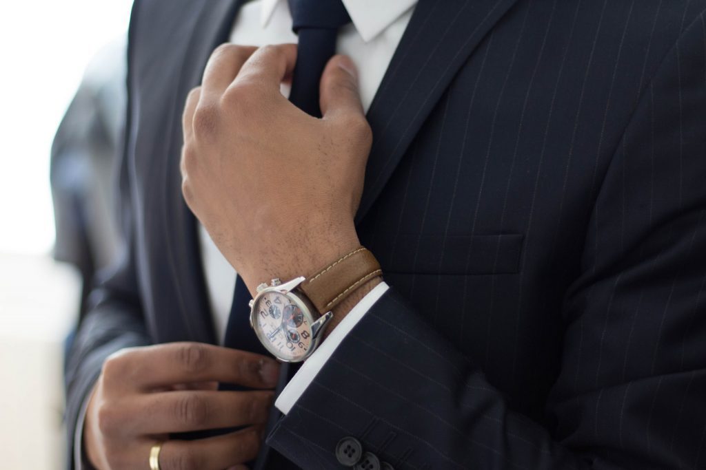 Man Wearing Watch and Adjusting His Tie