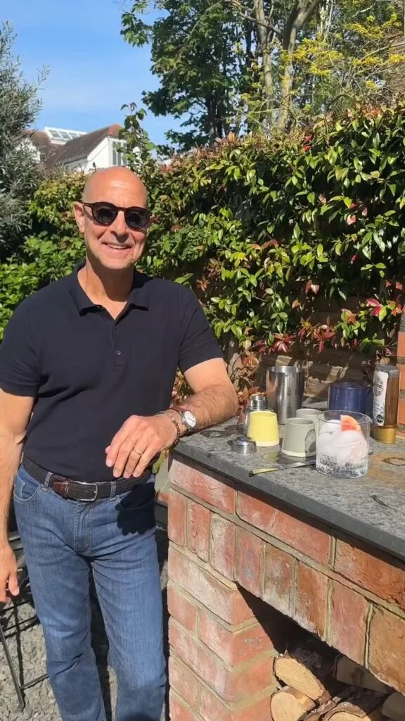 Stanley Tucci Wearing a Navy Polo Shirt with Jeans